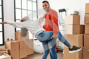 Young latin couple smiling happy dancing at new home