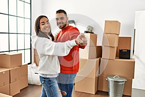 Young latin couple smiling happy dancing at new home
