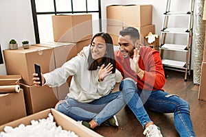 Young latin couple smiling happy doing video call using smartphone at new home