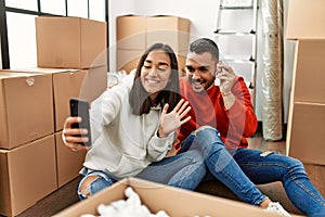 Young latin couple smiling happy doing video call using smartphone at new home