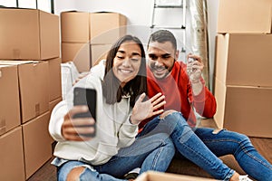 Young latin couple smiling happy doing video call using smartphone at new home