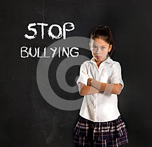 Young latin cute schoolgirl scared and sad and the words stop bullying text written with chalk