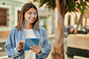 Young latin girl smiling happy using touchpad at the city