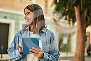 Young latin girl smiling happy using touchpad at the city