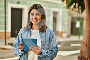 Young latin girl smiling happy using touchpad at the city