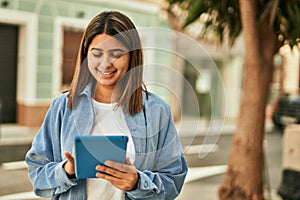 Young latin girl smiling happy using touchpad at the city