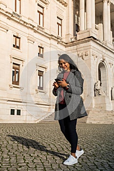 Young latin girl using the phone and looking to the camera while smile