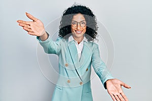 Young latin girl wearing business clothes and glasses looking at the camera smiling with open arms for hug