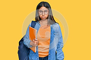 Young latin girl wearing student backpack and holding books depressed and worry for distress, crying angry and afraid