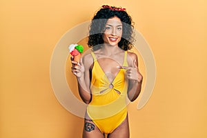 Young latin girl wearing summer style holding ice cream pointing finger to one self smiling happy and proud