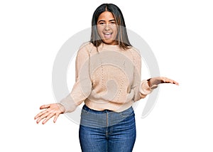 Young latin girl wearing wool winter sweater smiling cheerful with open arms as friendly welcome, positive and confident greetings