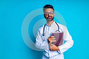 young latin hispanic medican man wear eye glasses with stethoscope in blue studio wall background