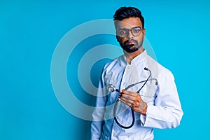young latin hispanic medican man wear eye glasses with stethoscope in blue studio wall background