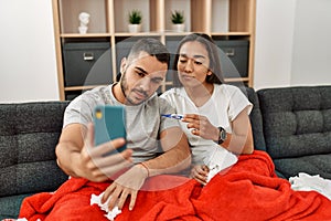 Young latin ill couple having medical teleconsultation using smartphone at home