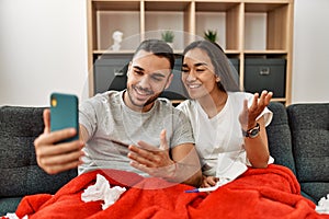 Young latin ill couple having medical teleconsultation using smartphone at home