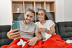 Young latin ill couple having medical teleconsultation using smartphone at home