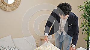 Young latin man business worker make bed at hotel room