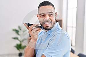 Young latin man business worker smiling confident talking on smartphone at office