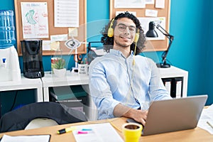 Young latin man business worker using laptop and headphones working at office