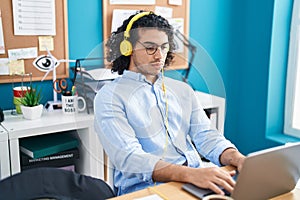 Young latin man business worker using laptop and headphones working at office