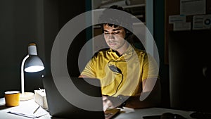 Young latin man business worker using laptop and headphones working at the office