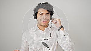 Young latin man business worker wearing headphones speaking over isolated white background