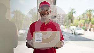 Young latin man delivery worker holding package at street