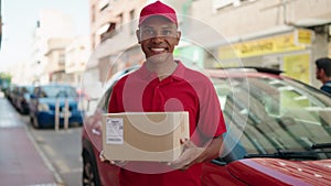Young latin man delivery worker holding package at street