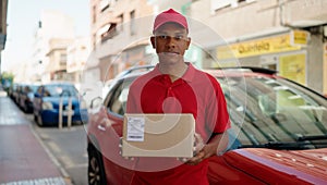 Young latin man delivery worker holding package at street