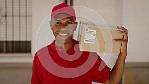 Young latin man delivery worker holding package at street