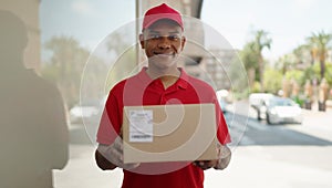 Young latin man delivery worker holding package at street