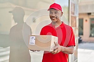 Young latin man delivery worker holding package at street