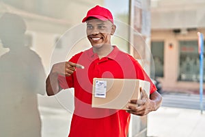 Young latin man delivery worker pointing with finger to package at street