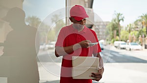 Young latin man delivery worker scanning package using smartphone at street