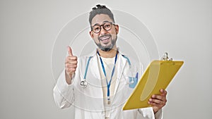 Young latin man doctor reading medical report doing thumb up gesture over isolated white background