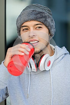 Young latin man drinking water runner portrait format winter running jogging sports training fitness