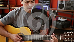 Young latin man musician singing song playing classical guitar at music studio