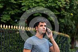 Young latin man in the park talking by mobile phone.