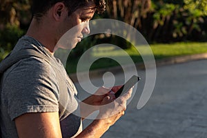 Young latin man in the park using the mobile phone.