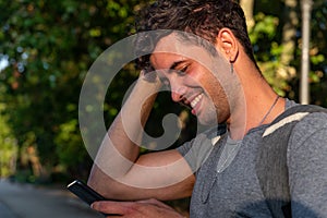 Young latin man in the park using the mobile phone.