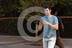 Young latin man in the park using the mobile phone.