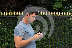 Young latin man in the park using the mobile phone.