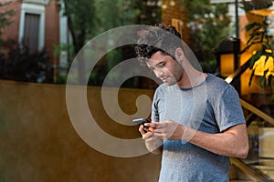 Young latin man in the park using the mobile phone.