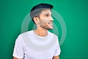 Young latin man smiling happy leaning on the wall at the city