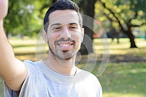 Young latin man taking a selfie in a park.