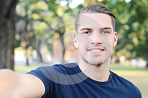 Young latin man taking a selfie in a park.