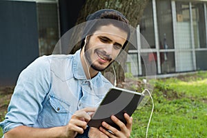Young latin man using tablet outdoors