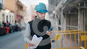 Young latin man worker with serious expression using smartphone at street
