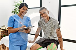 Young latin physioterapist woman asking to patient at the clinic