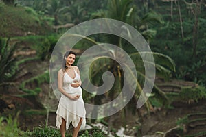 Young latin pregnant woman with husband with amazing view of Ubud rice terraces